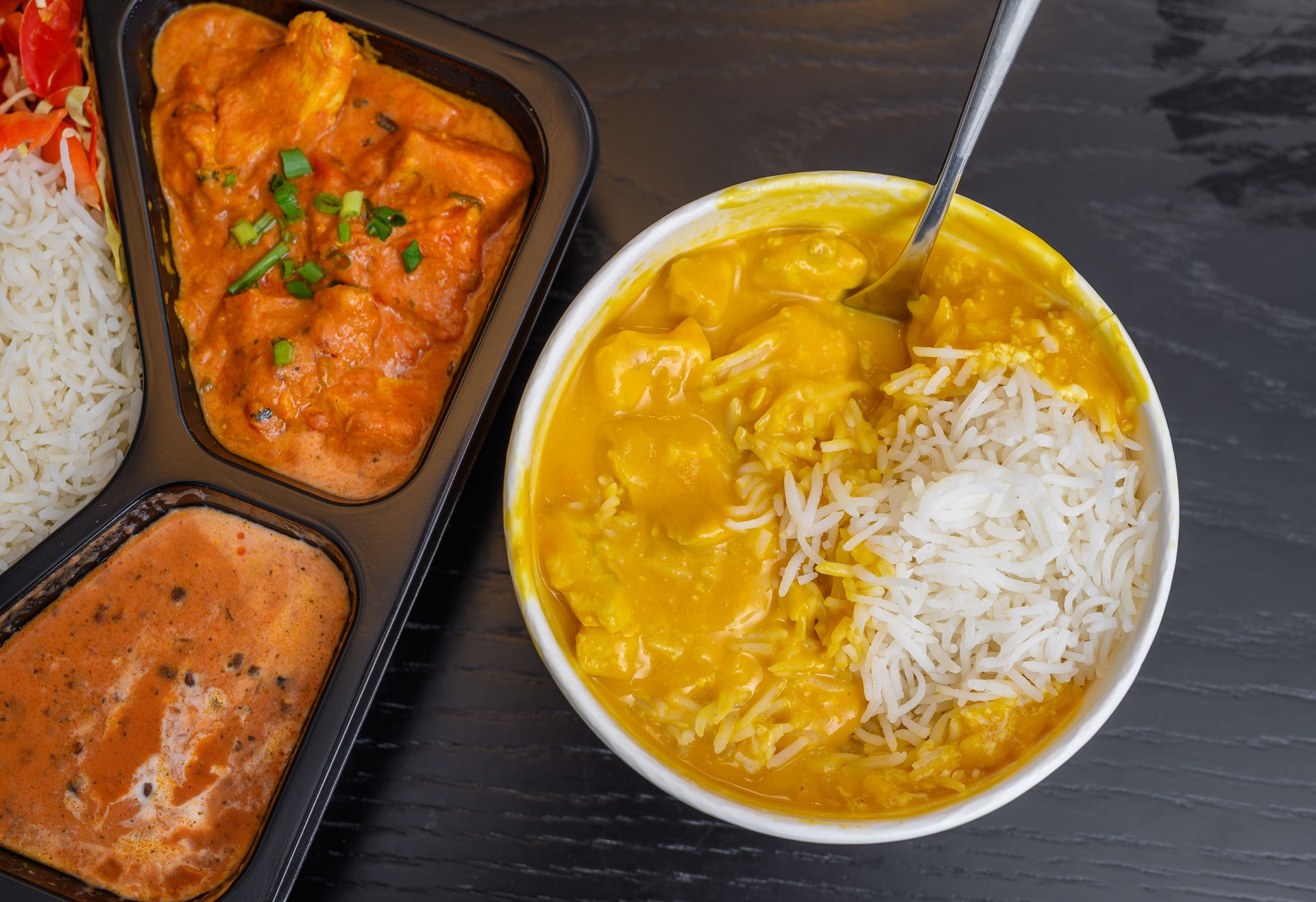 Indian cuisine catering, butter chicken and mango curry in plastic containers